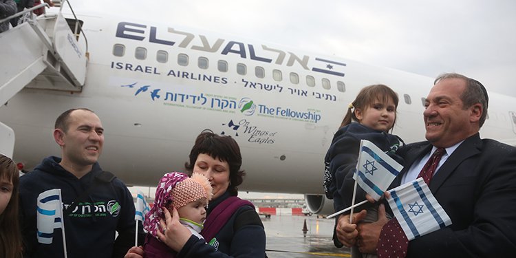 Rabbi Yechiel Eckstein outside deplaning plane on tarmac holding young girl