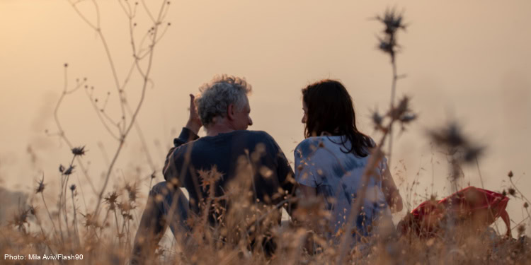 Man and woman sitting in a field looking at each other