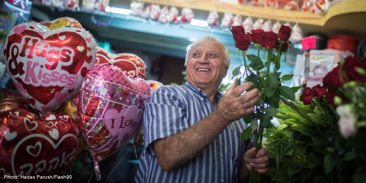 A man smiling surrounded by roses and balloons