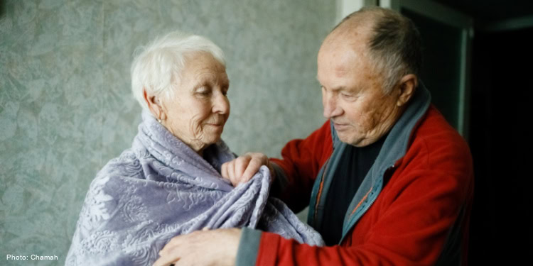 Elderly man putting on his wife's shawl