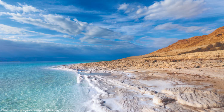 Beach in Israel with clear blue waters, sandy shoreline, and scenic coastal views under a partly cloudy sky.
