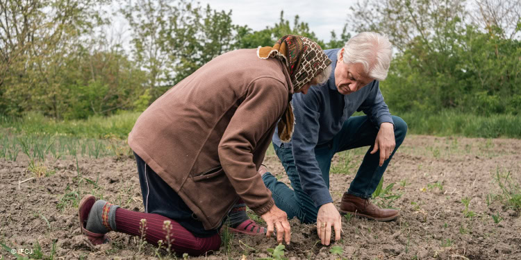 Two elderly individuals planting seeds in a field, symbolizing community support and hope for a better future through charitable work.