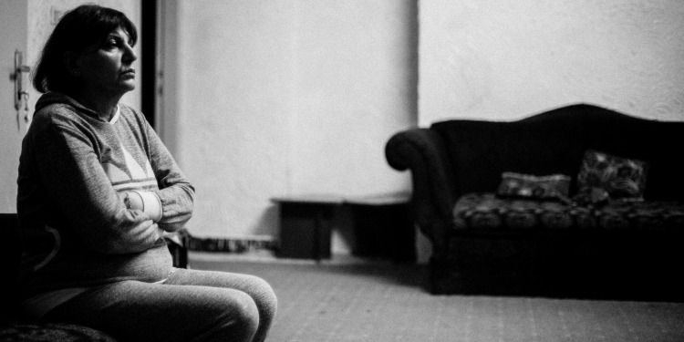 Black and white image of a woman kneeling on the floor while facing forward.