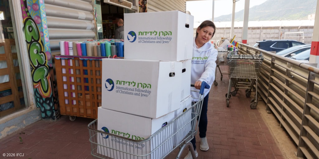 Woman delivering boxes of food aid from IFCJ to support vulnerable communities, emphasizing compassion and assistance for those in need.