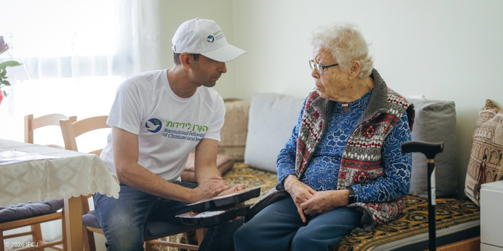 Elderly woman receiving support and companionship from a volunteer in a cozy home setting.