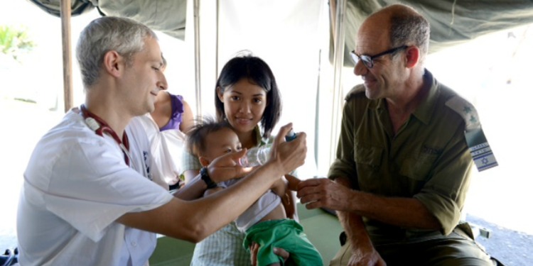 Doctor and solider helping a mother and her child.