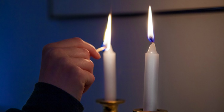 A hand lighting two candles.