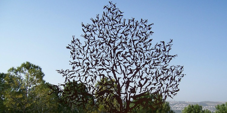 Statue of a tree with real trees behind it.