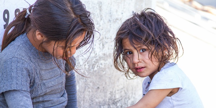 Two young girls kneeling on the ground.