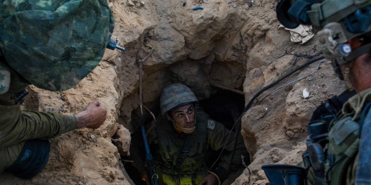 A soldier coming out of a tunnel with two other soldiers helping him.