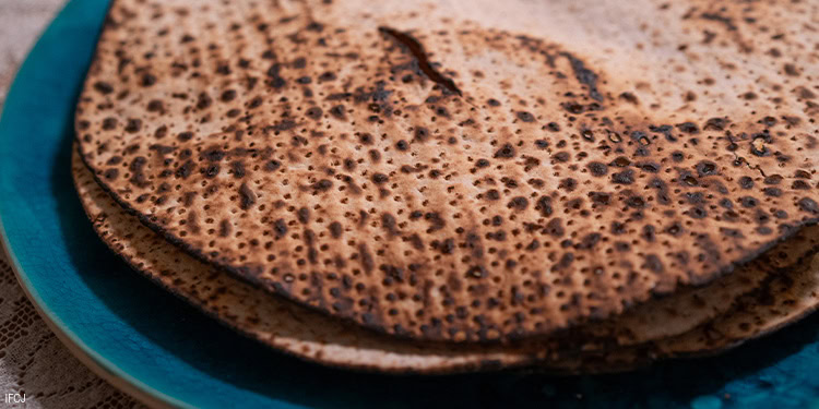 Flatbread with a crispy, browned surface on a vibrant blue plate, highlighting its texture and traditional preparation.