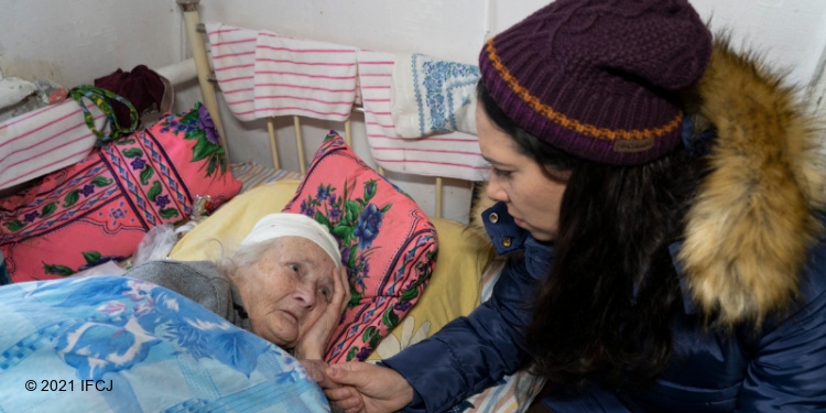 Yael Eckstein sitting bedside next to a sick elderly Jewish woman.