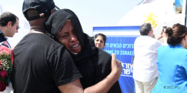 Ethiopian woman crying into a man's arms after just having completed aliyah.