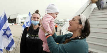 Yael Eckstein smiling at a baby who just made Aliyah.