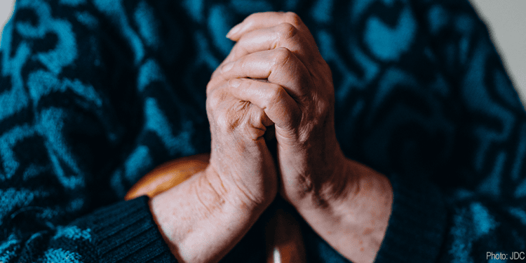 Close-up of elderly hands clasped in prayer, symbolizing hope and faith, with a blurred background.