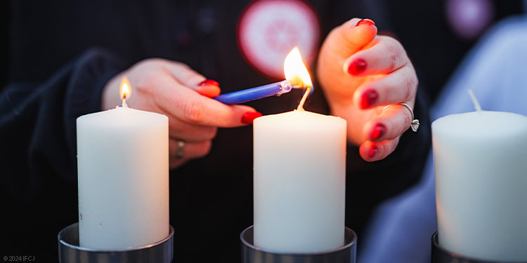 Hand lighting Hanukkah candles
