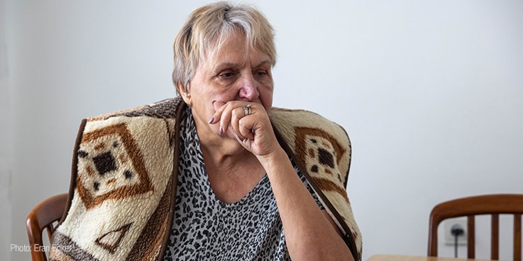 A sad elderly woman sitting at a table