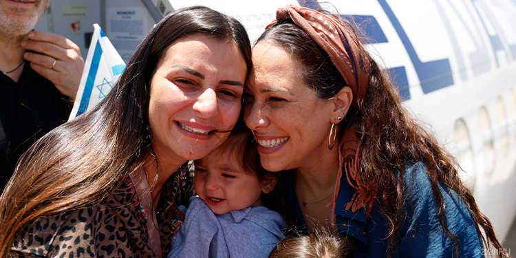 Two women and a young child sharing a joyful, emotional moment outdoors, symbolizing kindness and compassion.