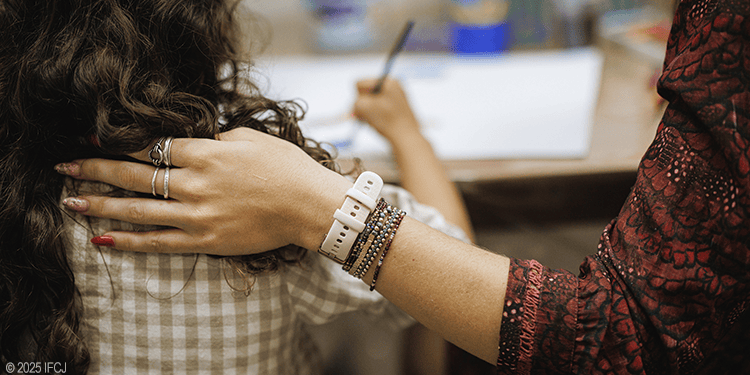 A caring volunteer gently places her hand on a person's shoulder, offering comfort and support in a community service setting.