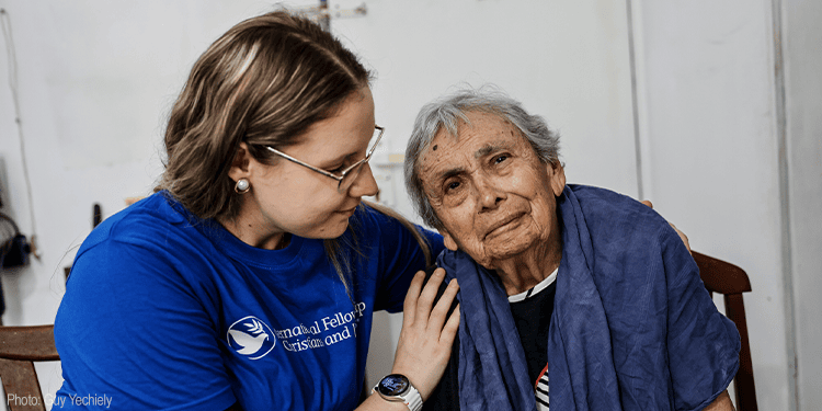 A young woman providing compassionate support to an elderly woman, demonstrating kindness and care, in a community or healthcare setting.