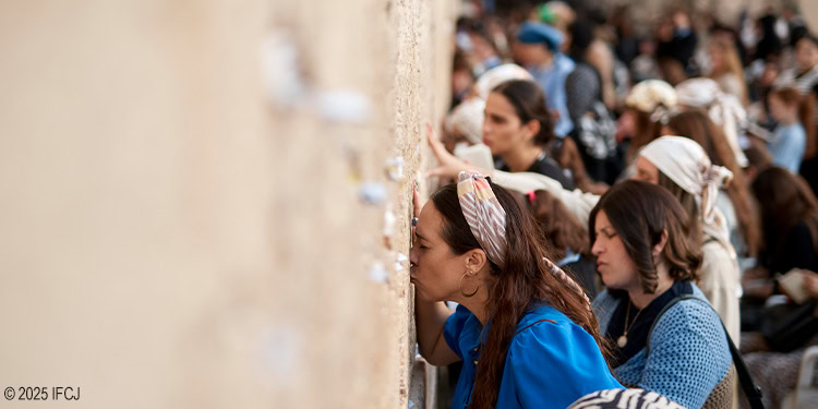 Devout individuals praying at the Western Wall, a sacred site in Jerusalem, during Tefillah bekotel, with many worshippers engaged in prayer and reflection.