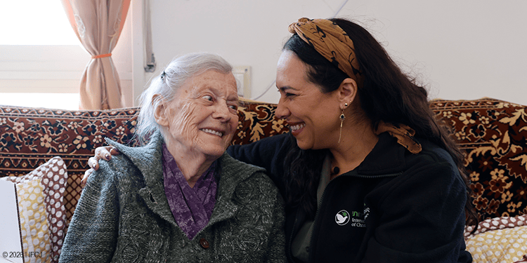 A young woman providing compassionate care and companionship to an elderly woman in a cozy home setting, highlighting kindness and support.