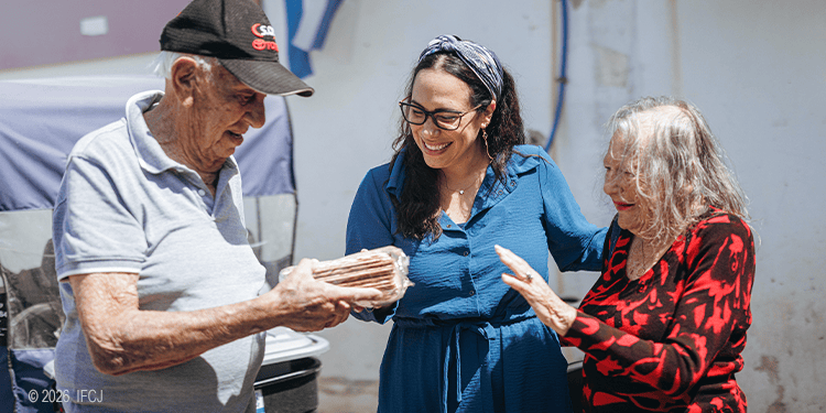 Yael giving a package of matzah to an elderly couple