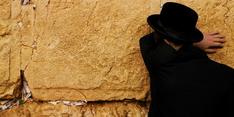 Man in all black praying at The Western Wall.