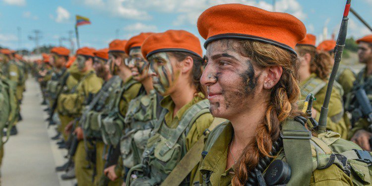 Several soldiers in uniform and face paint lined up together.