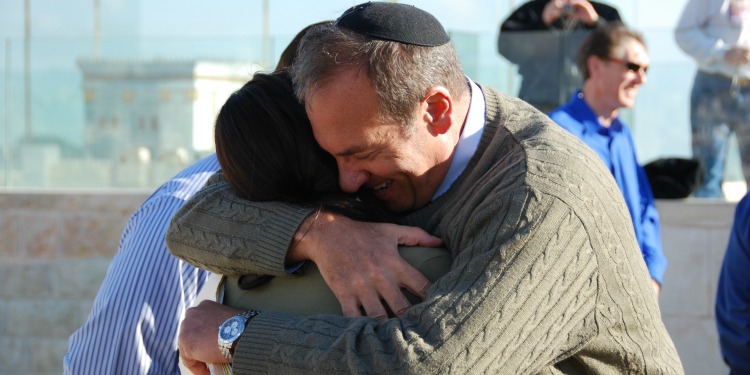 Rabbi Eckstein hugging someone and smiling.