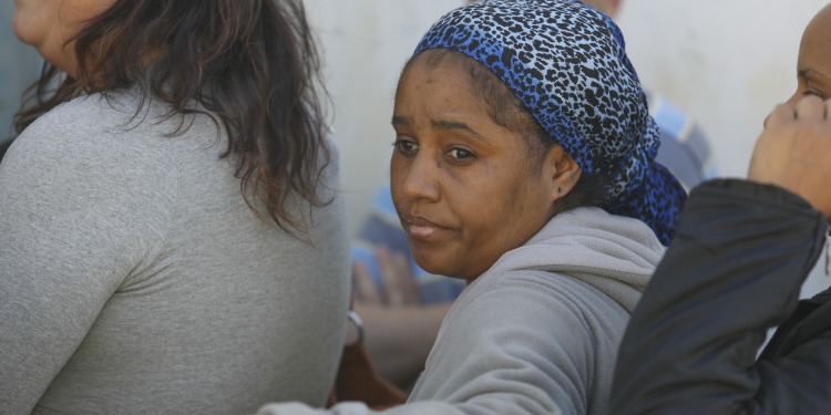 A woman standing in line looking sadly off into the distance.