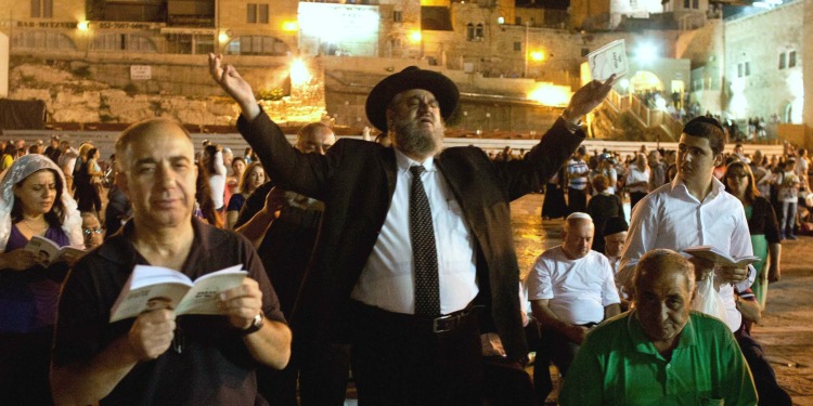 Several people giving praise while reading at the Western Wall.