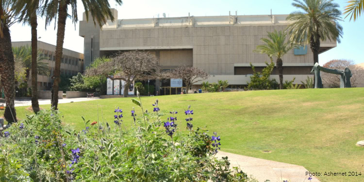 Exterior view of Tel Aviv University with palm trees, green lawn, and modern building in the background.