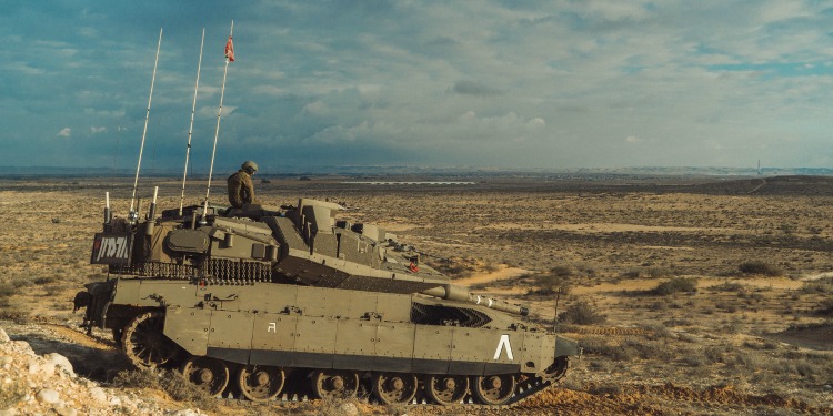 A soldier on a tank on sandy dry terrain.