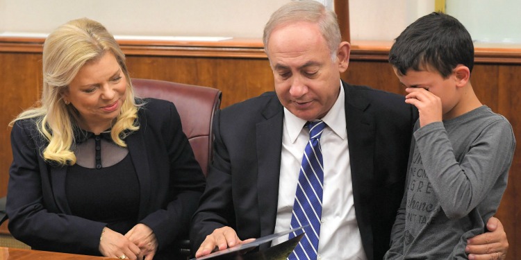 Bibi and his wife sitting with a young child flipping through a book.