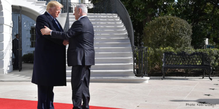 President Donald Trump and a man shaking hands outdoors, symbolizing support and partnership, with a staircase and greenery in the background.