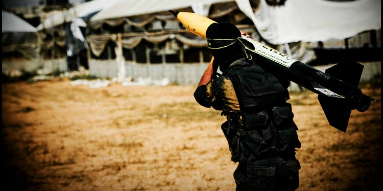 A man holding a large missile in the middle of the desert.