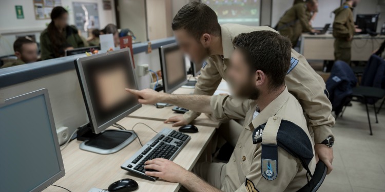 Two soldiers looking at a computer screen together.