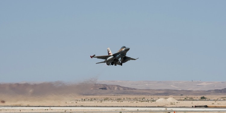 A plane making it's landing on a tarmac in the middle of the desert.