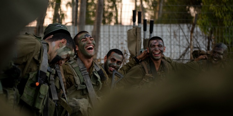 Four soldiers laughing together as they are standing together after a training exercise.