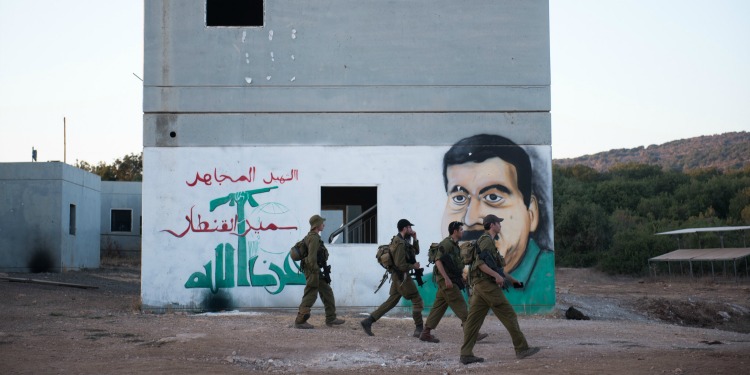 Four soldiers walking past a mural.