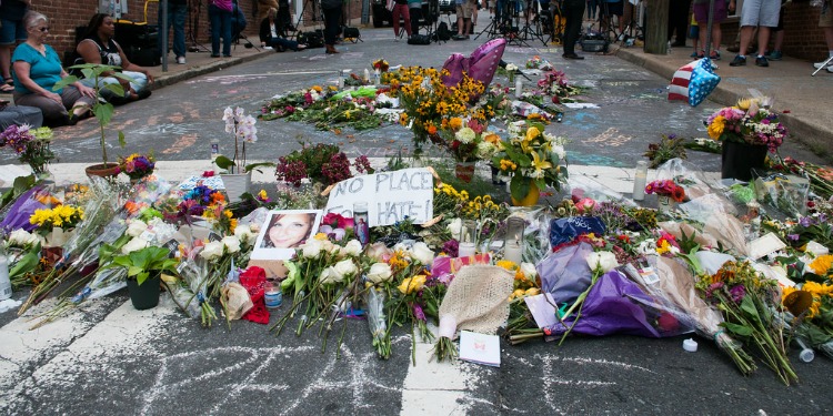 Many flowers placed against a sidewalk for a memorial