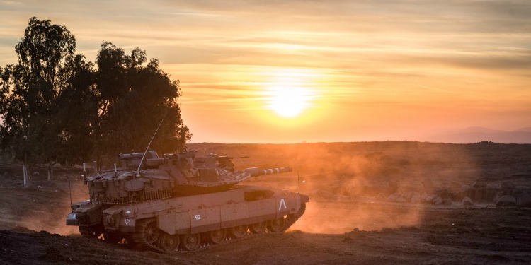 A tank in the middle of a field as the sun is about to rise.