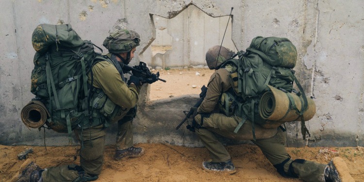 Soldiers looking into a hole of a concrete wall.
