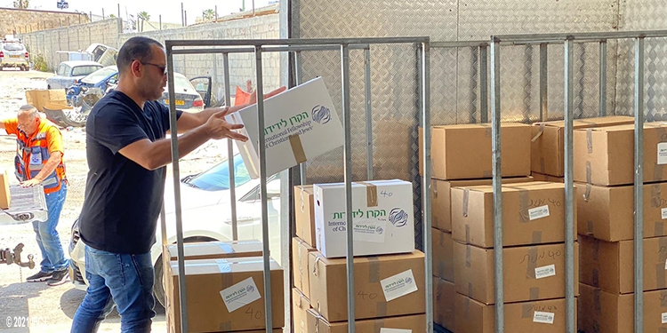 Man stacking IFCJ food boxes into a metal cage.