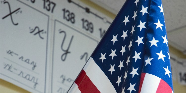 Close up on the stars portion of the American flag with a poster of the alphabet behind it.
