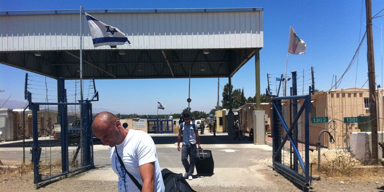 Two men leaving a facility with suitcases alongside them.