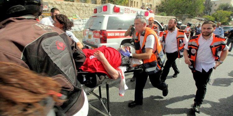 Four medical emergency workers pushing an injured male on a medical cart.