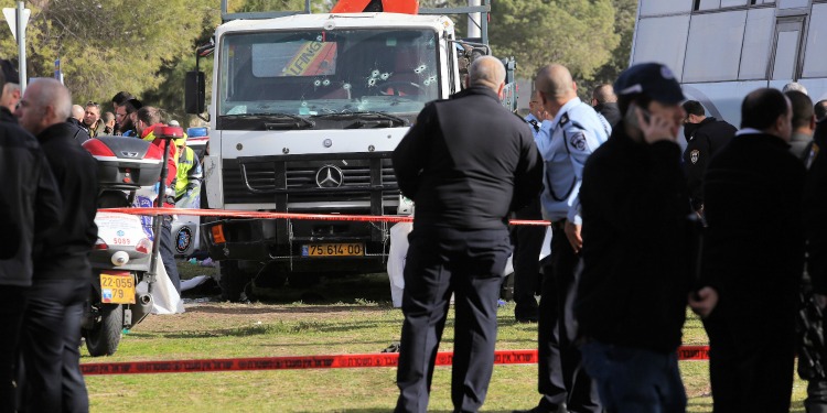 Large crowd of policemen and medics around a truck with several bullets through the front window.