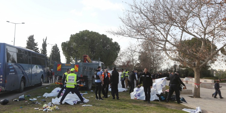 Several policemen, men in vests, and medics cleaning up an area that was terrorized.